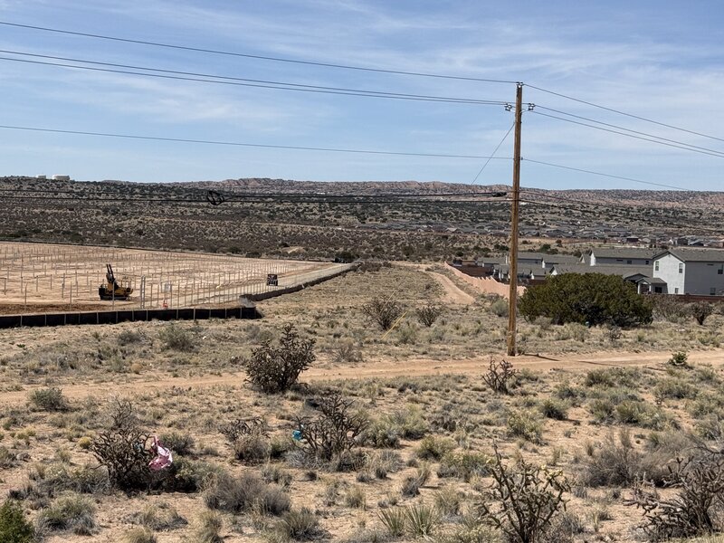 Solar farm construction in New Mexico — racking installation with community homes nearby